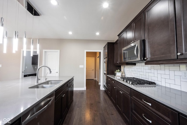 kitchen with a sink, stainless steel appliances, backsplash, dark wood-style floors, and baseboards