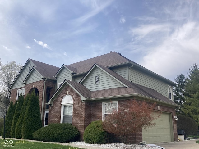 11458 Sutton Place Dr W, Carmel, IN 46032 - view of front facade featuring brick siding, a shingled roof, a garage, and driveway