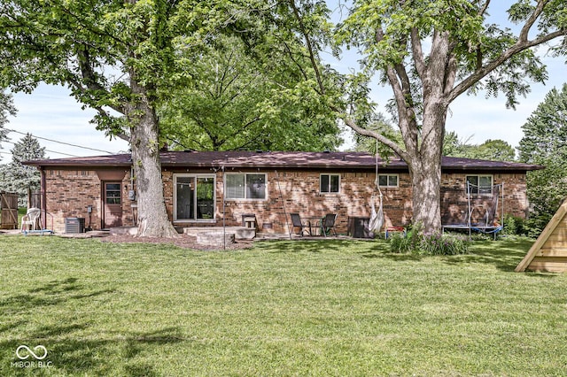 5427 Heights Ave, Indianapolis, IN 46237 - back of house with a trampoline, brick siding, and a lawn