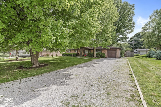 5427 Heights Ave, Indianapolis, IN 46237 - view of front facade with gravel driveway, an attached garage, a front yard, a storage unit, and brick siding