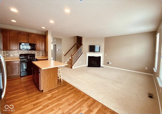 6304 El Paso St, Whitestown, IN 46075 - kitchen with black appliances, baseboards, a kitchen island, light countertops, and backsplash