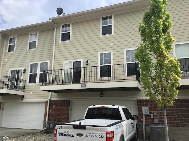 6304 El Paso St, Whitestown, IN 46075 - back of property featuring a garage, brick siding, central air condition unit, and a balcony