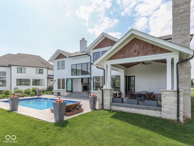 outdoor pool with a ceiling fan, a lawn, and a patio area