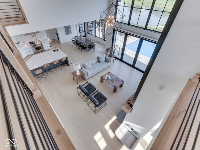 living area with a high ceiling, a chandelier, wood finished floors, and plenty of natural light