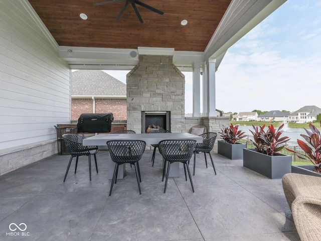 view of patio featuring an outdoor stone fireplace, ceiling fan, area for grilling, and outdoor dining area
