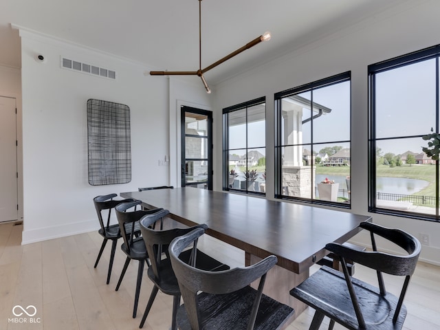 dining room featuring crown molding, baseboards, and light wood-style floors