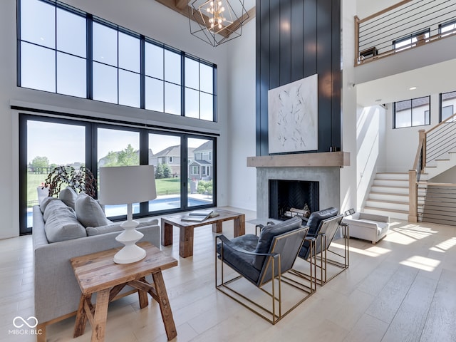 living room with a high ceiling, healthy amount of natural light, stairs, a chandelier, and a fireplace