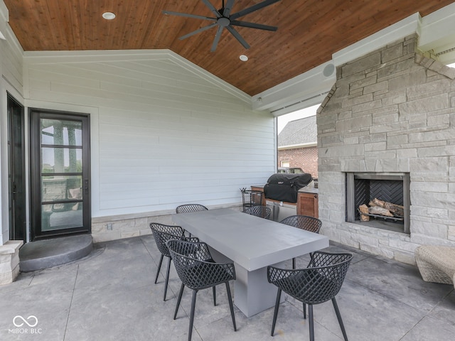 view of patio featuring an outdoor stone fireplace, ceiling fan, area for grilling, and outdoor dining area