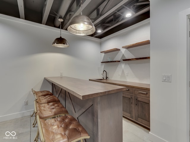 bar area with a sink, baseboards, and hanging light fixtures