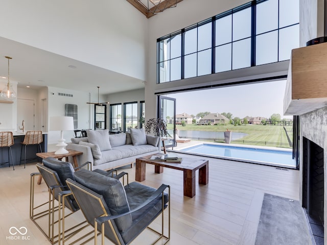 living room with a towering ceiling, a fireplace, and a water view
