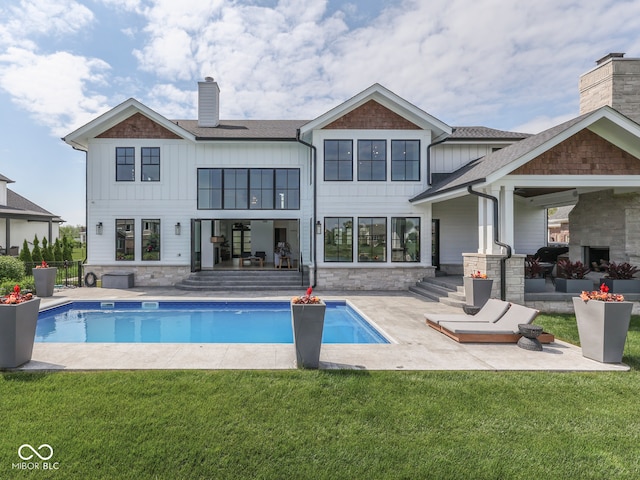 rear view of house with a chimney, a patio, and a yard