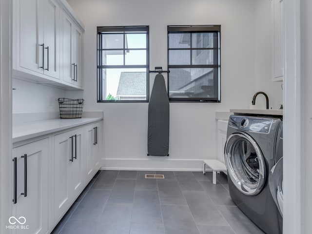 laundry room featuring cabinet space, washer / dryer, baseboards, and dark tile patterned floors