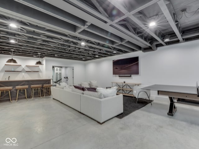 living area featuring concrete flooring and bar
