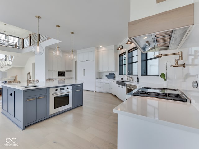 kitchen with white oven, range hood, paneled fridge, a sink, and white cabinets