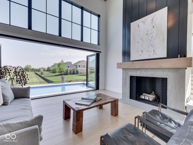 living room with a fireplace, a high ceiling, and light wood finished floors
