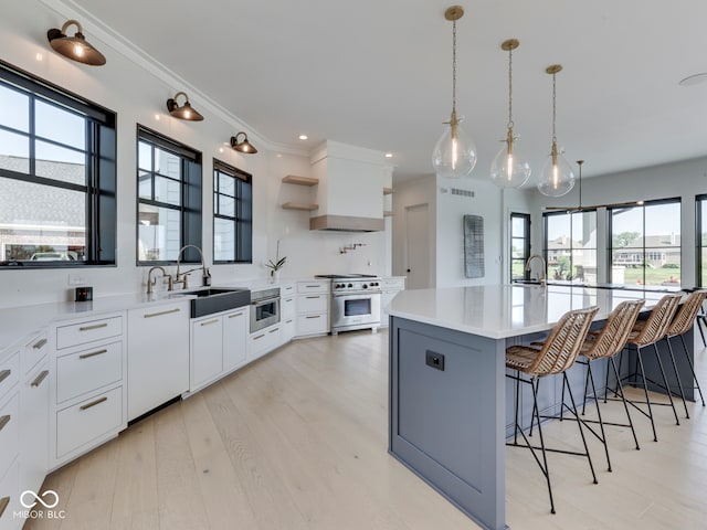 kitchen featuring stainless steel range, a sink, light countertops, a breakfast bar, and white cabinetry