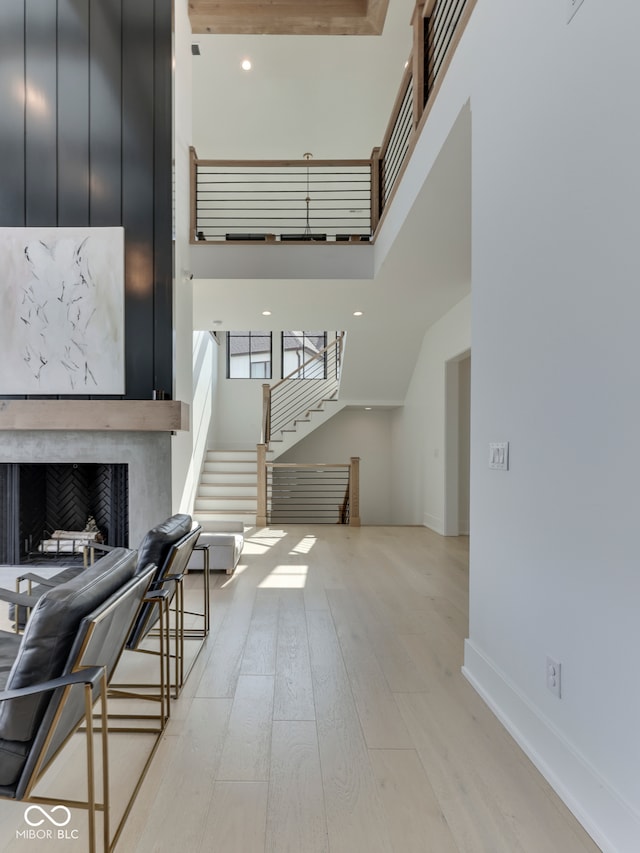 living room with light wood finished floors, stairs, a high end fireplace, a high ceiling, and recessed lighting