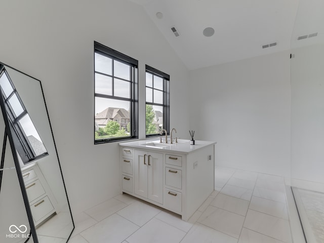 kitchen with a sink, vaulted ceiling, plenty of natural light, light countertops, and white cabinetry
