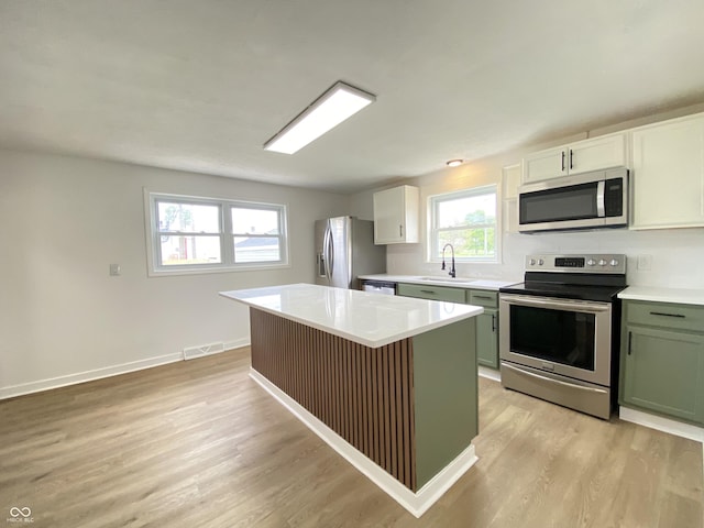 453 Illinois St, Fortville, IN 46040 - kitchen with appliances with stainless steel finishes, light wood-style floors, light countertops, a center island, and green cabinetry