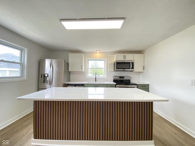 453 Illinois St, Fortville, IN 46040 - kitchen featuring stainless steel appliances, a sink, wood finished floors, baseboards, and white cabinetry