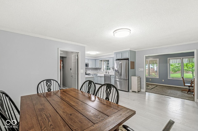 12388 Camberley Ln, Carmel, IN 46033 - dining area with crown molding, a textured ceiling, light wood-style floors, and baseboards
