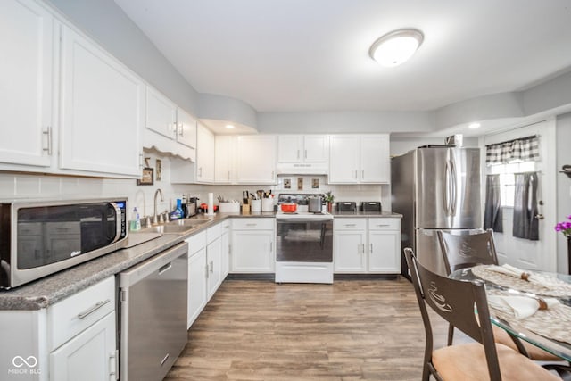 kitchen with stainless steel appliances, a sink, under cabinet range hood, white cabinets, and recessed lighting