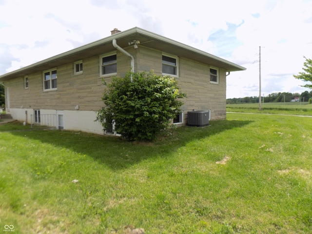 9739 S County Road 825 E, Cloverdale, IN 46120 - view of side of home featuring stone siding, a chimney, a lawn, and central air condition unit