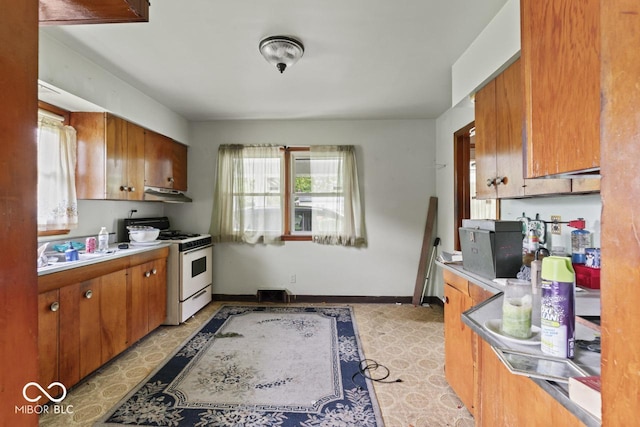 2840 W 12th St, Anderson, IN 46011 - kitchen with white gas range oven, plenty of natural light, and brown cabinetry