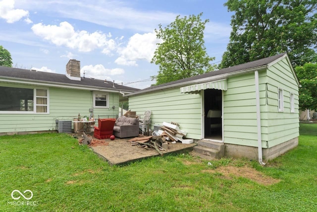 2840 W 12th St, Anderson, IN 46011 - rear view of house with entry steps, a yard, a chimney, and central AC unit