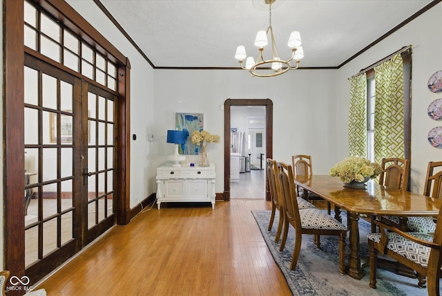1132 Evison St, Indianapolis, IN 46203 - dining area with ornamental molding, arched walkways, a chandelier, french doors, and light wood finished floors