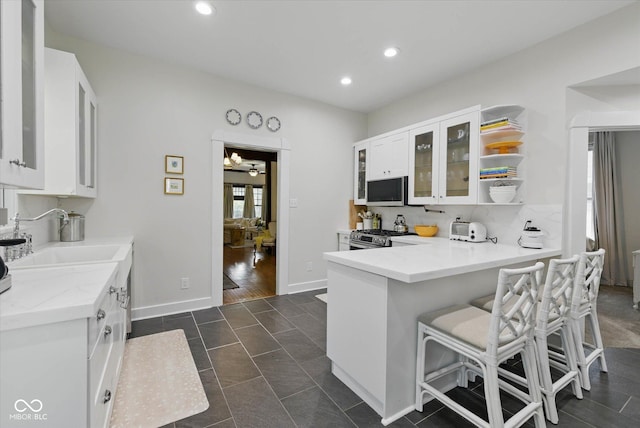 1132 Evison St, Indianapolis, IN 46203 - kitchen with a sink, white cabinetry, stainless steel appliances, recessed lighting, and glass insert cabinets