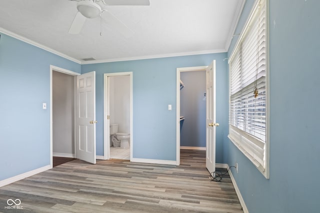 522 E County Road 1000 S, Clayton, IN 46118 - unfurnished bedroom with wood finished floors, crown molding, baseboards, connected bathroom, and a walk in closet