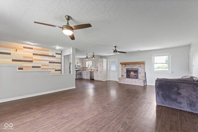 522 E County Road 1000 S, Clayton, IN 46118 - living room with a ceiling fan, a brick fireplace, baseboards, dark wood-style floors, and an accent wall