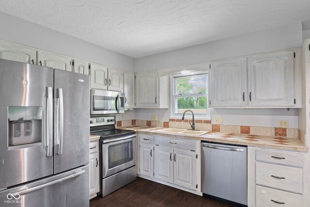 522 E County Road 1000 S, Clayton, IN 46118 - kitchen featuring appliances with stainless steel finishes, a sink, tile countertops, dark wood-style floors, and white cabinets