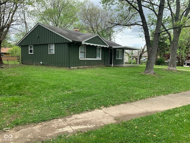 3742 N Wittfield St, Indianapolis, IN 46235 - view of home's exterior featuring board and batten siding, a lawn, a chimney, and roof with shingles
