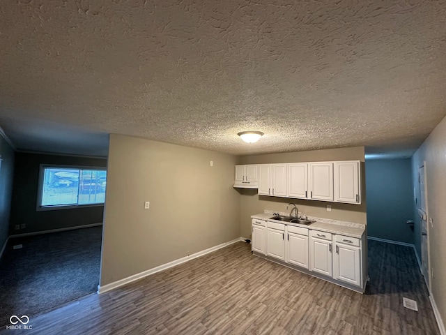 3742 N Wittfield St, Indianapolis, IN 46235 - kitchen with a sink, baseboards, light countertops, a textured ceiling, and wood finished floors