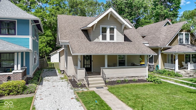 344 N Whittier Pl, Indianapolis, IN 46219 - view of front facade featuring covered porch, roof with shingles, gravel driveway, and a front lawn