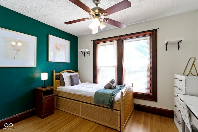 344 N Whittier Pl, Indianapolis, IN 46219 - bedroom featuring baseboards, light wood-style flooring, a textured ceiling, and a ceiling fan
