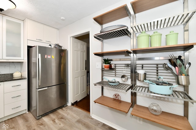 1310 Kings Cove Ct, Indianapolis, IN 46260 - kitchen with freestanding refrigerator, open shelves, light wood-style floors, white cabinets, and dark stone countertops