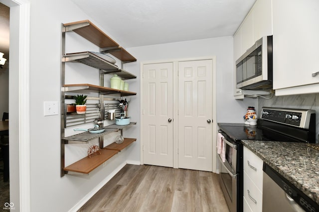 1310 Kings Cove Ct, Indianapolis, IN 46260 - kitchen with stainless steel appliances, light wood-style floors, white cabinetry, dark stone counters, and baseboards