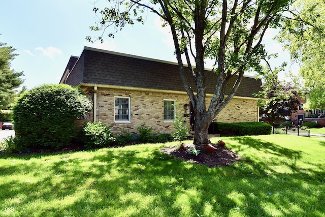 1310 Kings Cove Ct, Indianapolis, IN 46260 - view of home's exterior with brick siding, a lawn, and roof with shingles