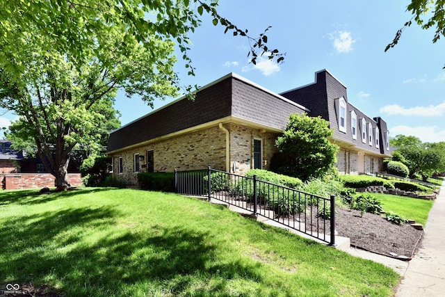 1310 Kings Cove Ct, Indianapolis, IN 46260 - view of home's exterior with brick siding, mansard roof, a lawn, and roof with shingles