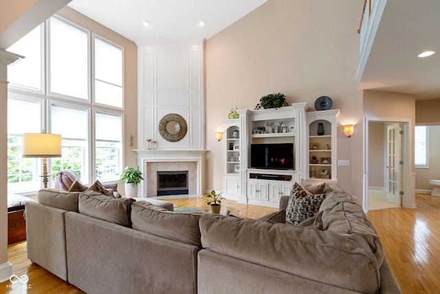 14094 Pecos Ct, Carmel, IN 46033 - living area with a high ceiling, a large fireplace, light wood-style floors, recessed lighting, and baseboards