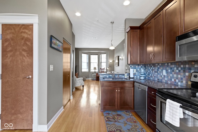 404 E New York St E Unit 406, Indianapolis, IN 46202 - kitchen with stainless steel appliances, light wood-style flooring, a peninsula, decorative backsplash, and a sink