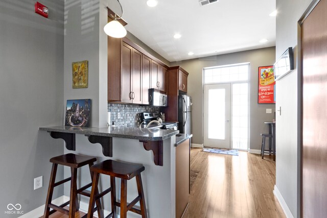 404 E New York St E Unit 406, Indianapolis, IN 46202 - kitchen featuring stainless steel appliances, a kitchen breakfast bar, backsplash, recessed lighting, and light wood finished floors