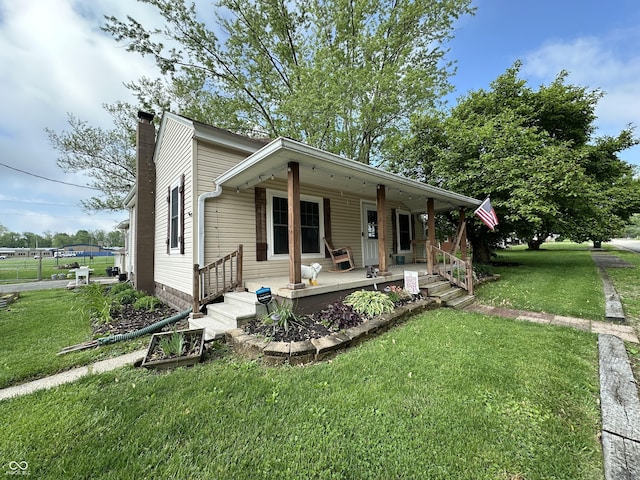 view of front facade with covered porch, a front yard, and a chimney