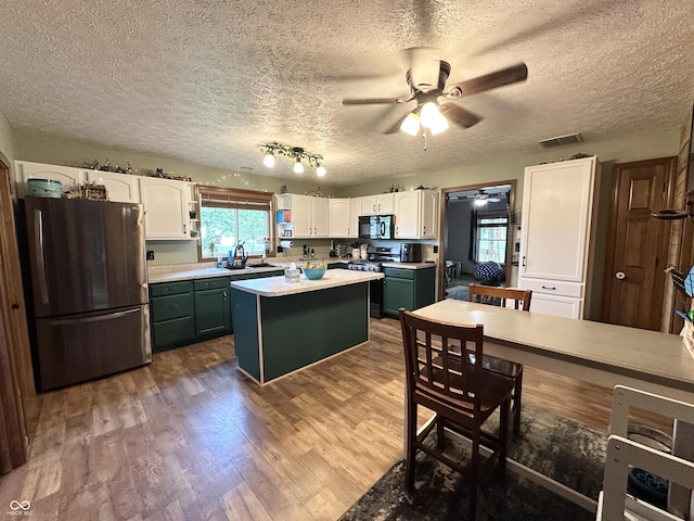 kitchen featuring stainless steel appliances, white cabinetry, a ceiling fan, plenty of natural light, and a textured ceiling