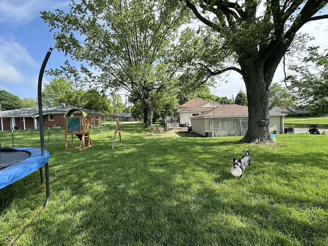 view of green lawn featuring a trampoline and a playground