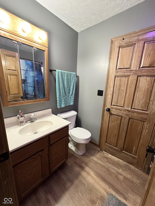 full bath with wood finished floors, toilet, vanity, and a textured ceiling