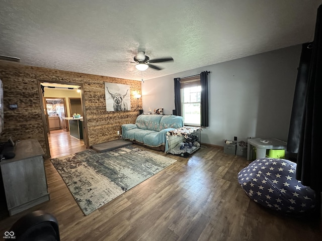 bedroom featuring wood finished floors, a textured ceiling, baseboards, and ceiling fan